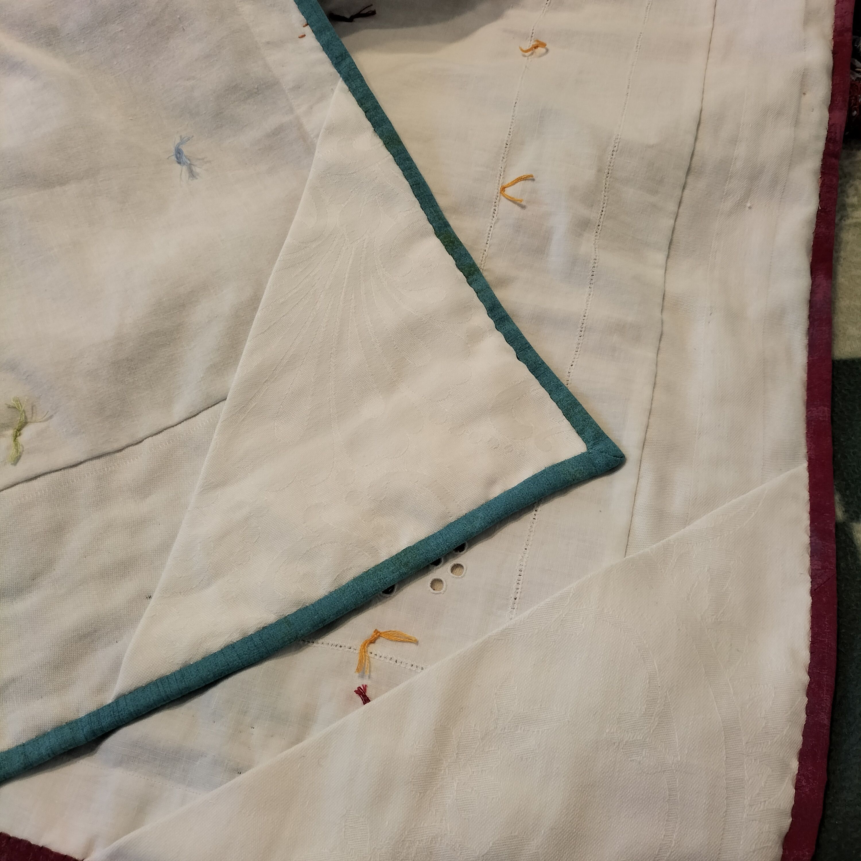 The white back of a quilt showing pink and blue binding stitched into place.