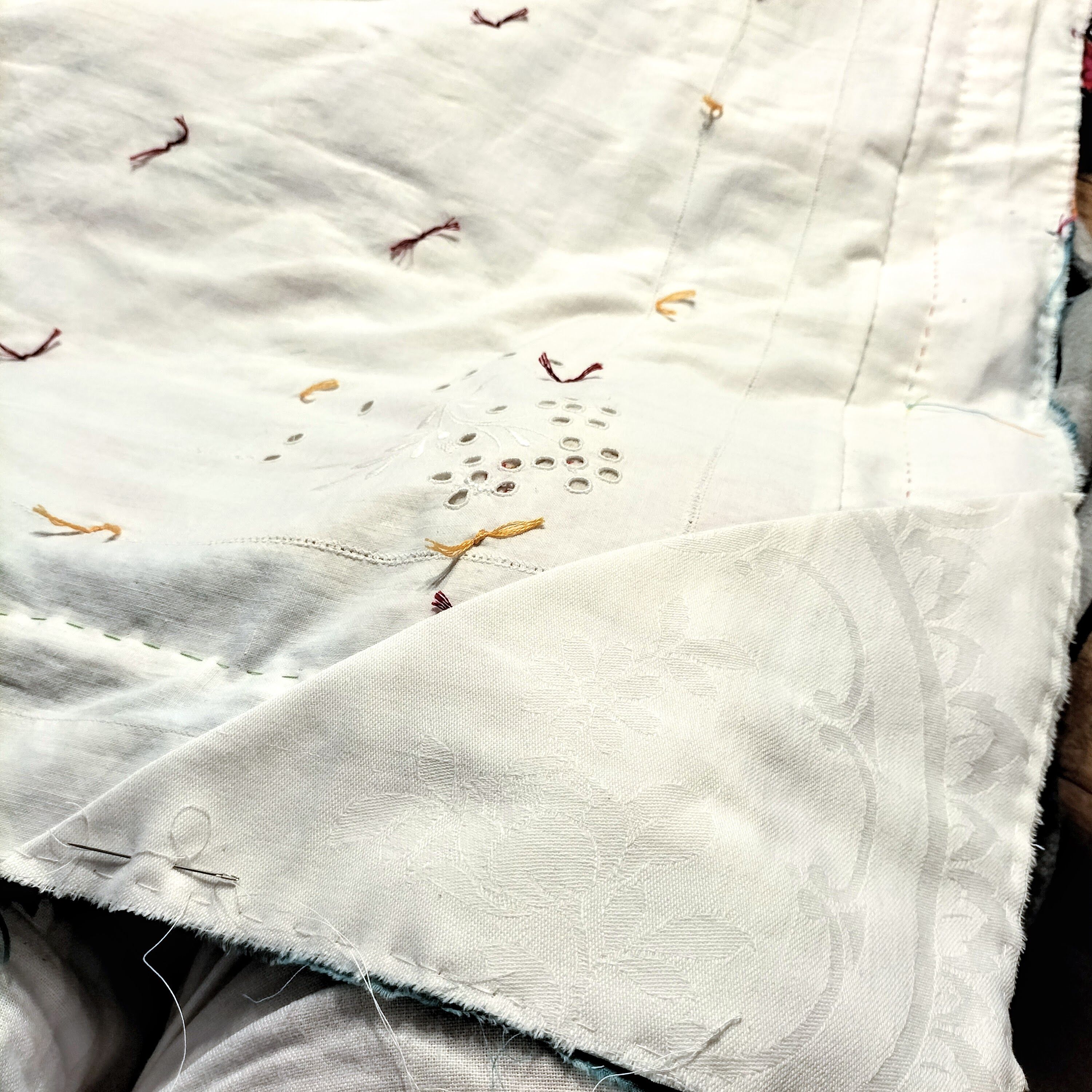 White damask fabric quilt back, with a triangular corner pocket and multicoloured ties.