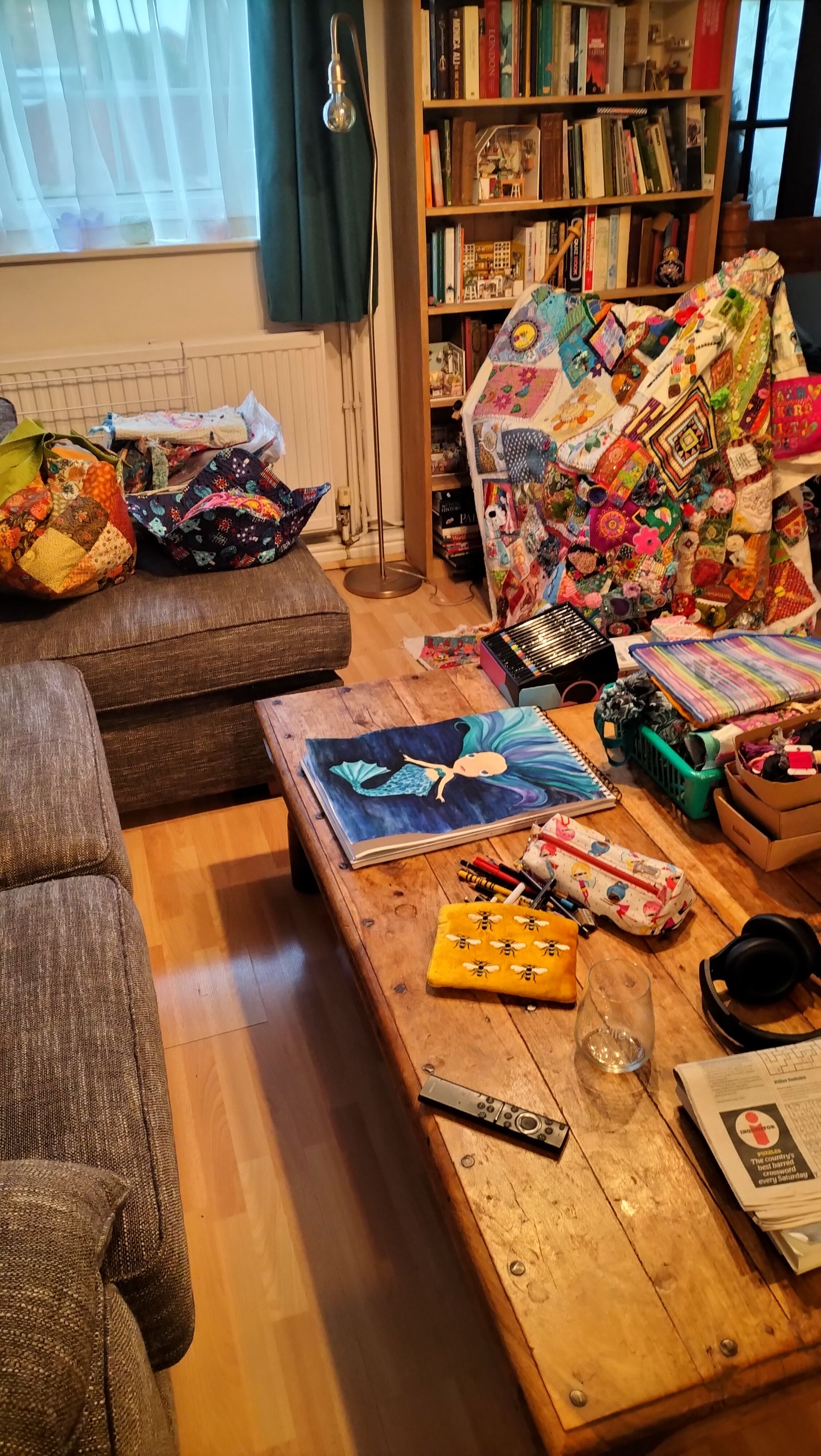 A sitting room with various colourful craft projects on the sofa and table, and a quilt in the background.