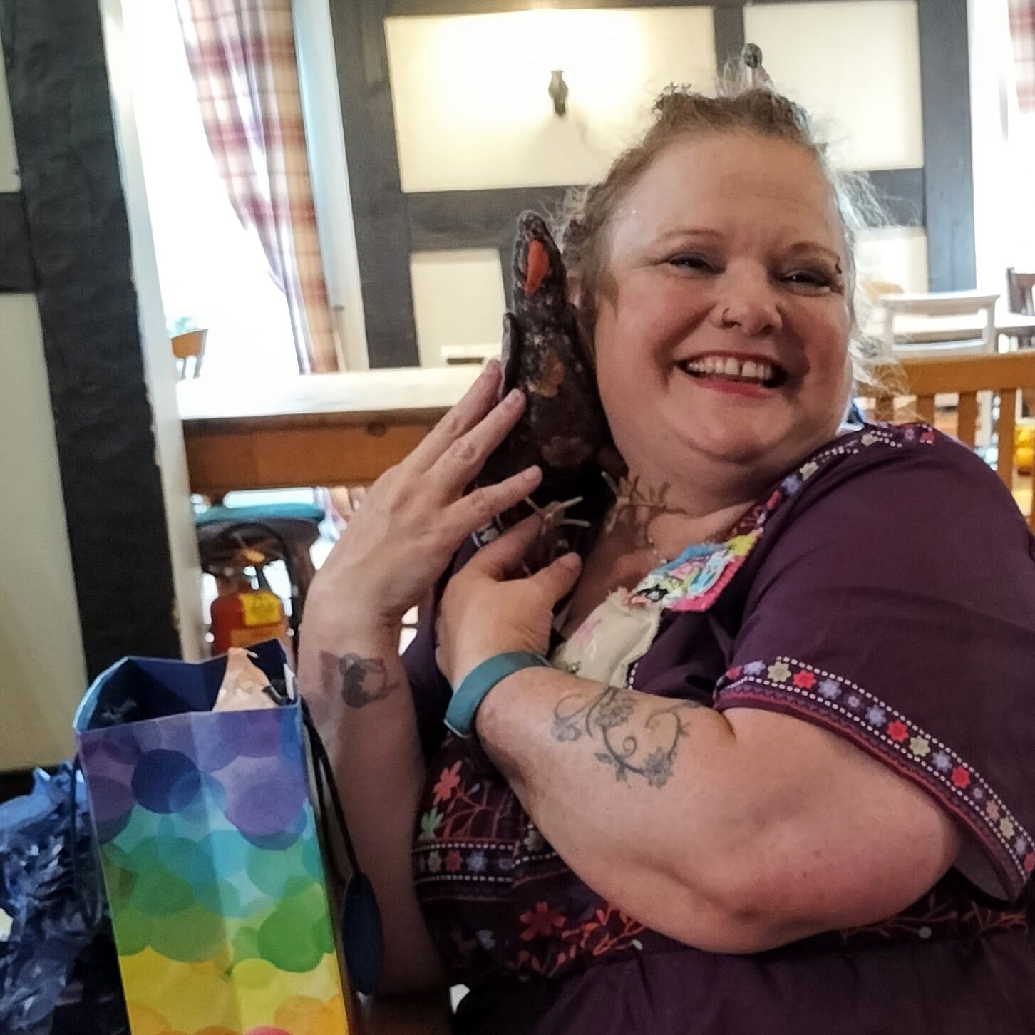 A smiling woman hugging a stuffed fabric bird